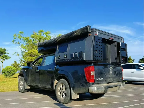 Nissan Navara with a slide-on camper and awning rolled up, rear view