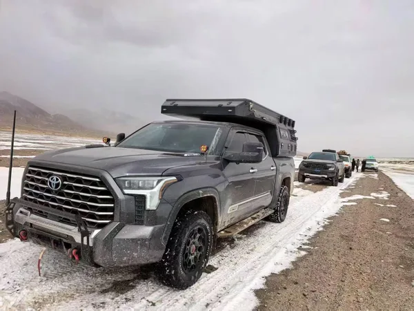 Toyota Tundra with a slide-in camper on a snowy plateau road