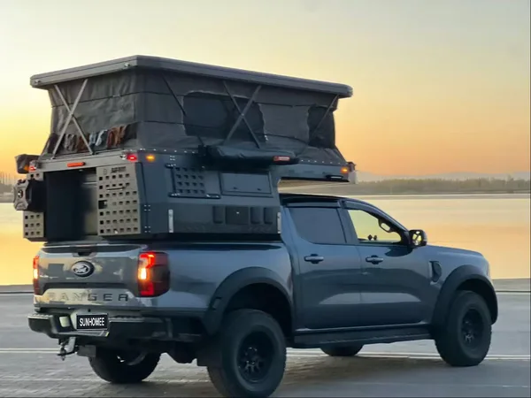 Ford Ranger with the slide-in camper roof raised at sunset by the sea