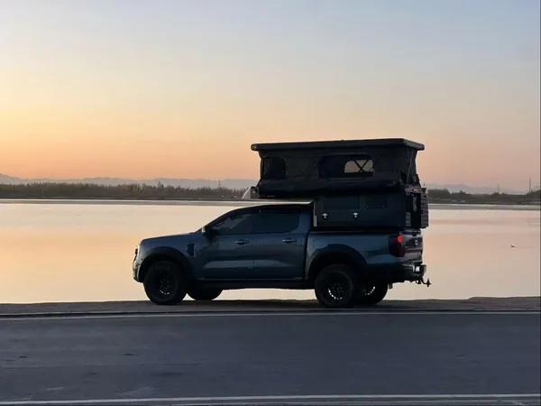 Slide-in camper on a pickup at sunset by the water