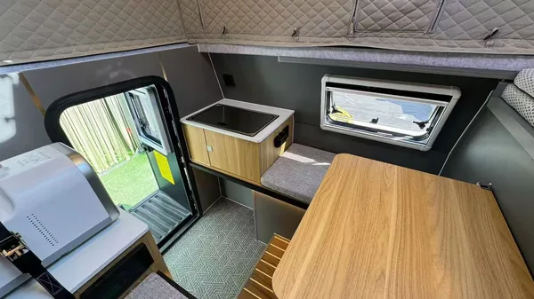 Slide-in camper interior with wood table and window