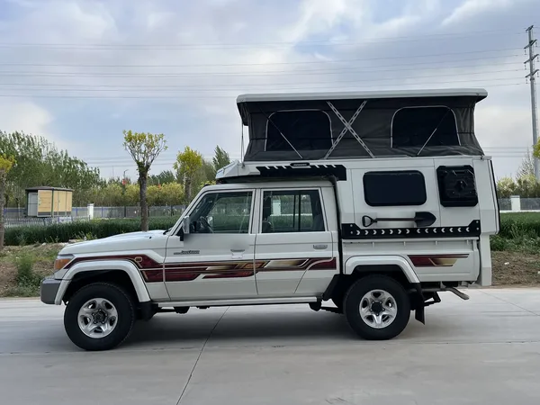White Toyota Land Cruiser 79 with a SUNHOMEE flatbed camper, pop-up roof raised, side view