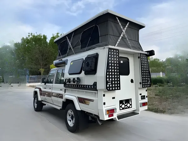 White Toyota Land Cruiser 79 with a SUNHOMEE flatbed camper, pop-up roof raised, rear view
