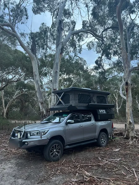 Toyota HiLux with a SUNHOMEE slide-on camper among gum trees