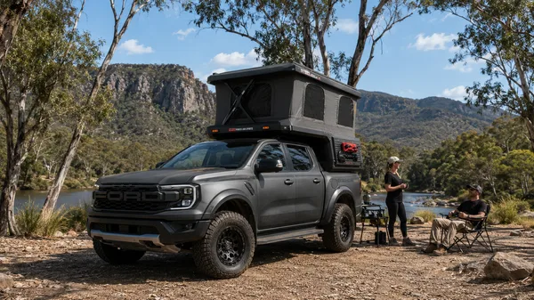Grey pickup with a slide-in camper at camp in a canyon