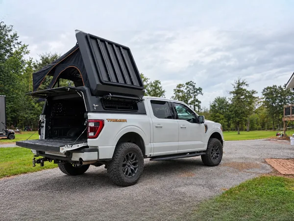 Stealth pop-up topper with the tent open on a white Ford F-150, rear three-quarter view