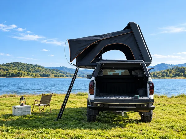 Stealth pop-up topper open on the grass by a lake, rear view