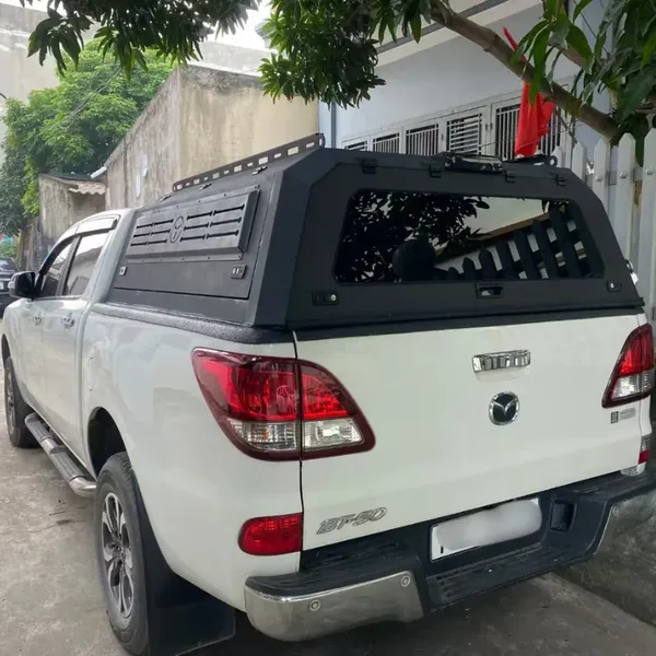 Black SUNHOMEE truck topper with roof rack on a white Mazda BT-50