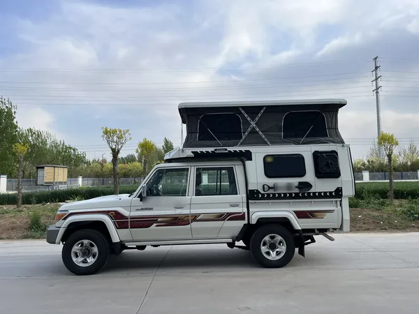Toyota LandCruiser 79 with a white SUNHOMEE slide-on camper, roof raised