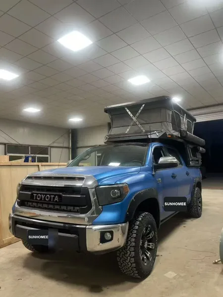 Blue Toyota Tundra with a SUNHOMEE slide-in camper, roof raised